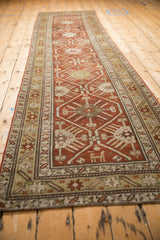 Low angle view of an antique Caucasian runner's repeating geometric motifs in rust and gold.