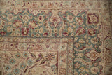 Worn pile on the corner of a distressed Kerman carpet showing teal and burgundy floral borders.