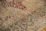 Worn, low pile texture of a Persian Kerman's floral border in dusty teal and burgundy.