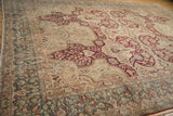 Angled view of the distressed vintage Kerman carpet's corner and dusty teal border.
