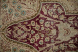 Distressed Kerman rug showing worn burgundy trefoil motifs and teal flowers over an ivory foundation.