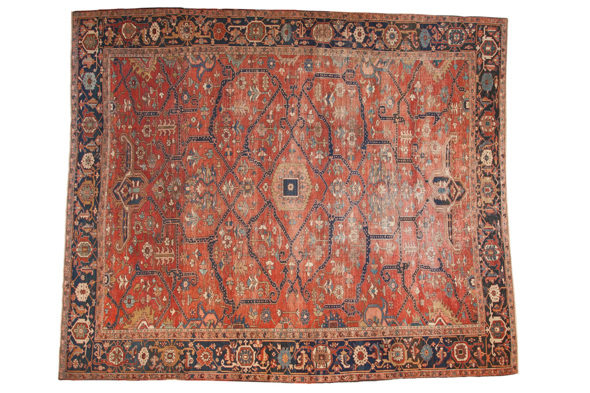 Antique Heriz carpet with interconnected vines forming a geometric lattice design in brick red and navy blue.