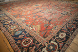 Angled view of an antique Heriz carpet's corner, showing the navy Samovar turtle border and geometric field.