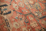 Close-up of a brick red Heriz carpet showing the weave, pile, and exposed knot heads.