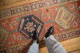Brick red field, sapphire blue medallion with floral blossoms, and pomegranate border on antique Persian runner.