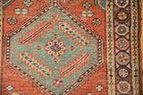 Antique Northwest Persian runner's teal floral medallion, brick red field, and pomegranate border.