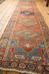 Close-up of antique Northwest Persian runner, brick red field, serrated leaves, blue pomegranate border.
