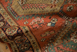 Folded antique Persian runner revealing brick red field, serrated leaves, and jade green border.