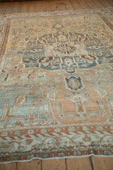 Angled view of a distressed Baktiari carpet, showing the low pile and heavily abrashed floral pattern.