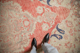 Abrashed soft red field and distressed low pile of a vintage Oushak rug with navy blue botehs.