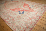 Angled view of a distressed Oushak carpet's mostly even wear and soft red corner spandrel.