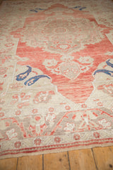Low angle view of a distressed Oushak carpet's soft red medallion and time-softened pile.