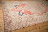 Angled perspective on a distressed Oushak carpet showing the abrashed red field and corner spandrels.