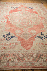 Angled view down a distressed Oushak carpet, showing the soft red medallion and navy botehs.