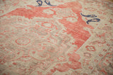 Navy blue boteh motifs and low-pile texture on the soft red and beige field of a vintage Oushak carpet.