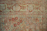 Distressed antique Sarouk rug's main border with pomegranate red palmettes and slate blue floral field.