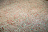 Distressed texture of muted floral sprays in pomegranate and slate blue on an antique Sarouk rug.