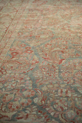 Distressed Sarouk rug displays worn slate blue field, pomegranate, and blush floral motifs.