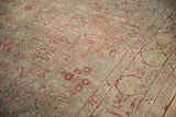 Distressed antique Sarouk carpet showing worn floral sprays and a palmette border in muted red and blue.