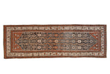 Distressed vintage Hamadan runner with sprawling floral vines in charcoal, rust, and silver tones.