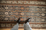 The decorative, low-pile texture of a vintage Hamadan runner with floral and animal motifs.