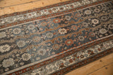 Angled view of the meandering vine border and distressed floral field on a vintage Hamadan runner.
