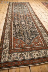 Angled view down a distressed Hamadan runner with charcoal, rust, and silver floral vine patterns.