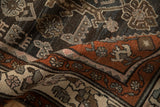 Softly worn pile of a vintage Hamadan rug showing rust-colored floral borders and charcoal motifs.