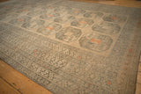 Angled view of the distressed Ersari carpet's geometric borders and repeating gul motifs.