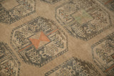 Low, even pile of a distressed Ersari carpet showing geometric gul motifs in teal and orange.
