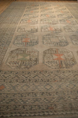 Low-angle view along the geometric border and repeating guls of a vintage distressed carpet.