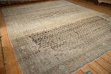 Angled view of a vintage Persian Bijar carpet with a distressed low pile and heavy abrashes.