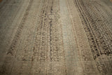 Low-angle view of a distressed Bijar carpet showing heavy color abrashes and time-softened texture.