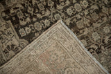 Folded corner of a distressed Bijar carpet showing its hand-knotted foundation and secured side cord.