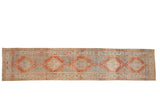 Distressed vintage Heriz rug runner with geometric diamond medallions in faded red, sand, and powder blue.