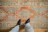 Looking down on the faded red and powder blue geometric pattern of a distressed Heriz rug.