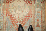 Evenly worn pile on a vintage Heriz runner, highlighting its geometric red and blue medallion.
