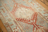 Angled view of a distressed Heriz runner's stepped diamond medallion and faded low-pile texture.