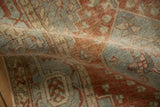 Close view of the distressed, hand-knotted pile in faded red and powder blue.