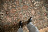 The decorative, worn texture of a Persian Mahal rug with raspberry and gold floral patterns.