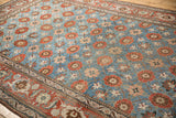 Angled view of the floral Mina Khani pattern and ornate red border on a distressed Veramin carpet.