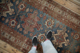 Overhead view of the distressed texture and repeating medallions on a vintage Malayer runner.