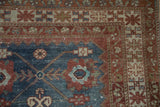 Geometric crab-style border in pomegranate red and beige on a distressed indigo blue Malayer rug.
