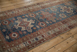 Angled view of a distressed Malayer runner highlighting repeating indigo and red geometric medallions.