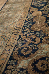 Elaborate sand-toned border and navy field with scrolling tendrils on a vintage Kerman carpet.