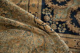 Softly folded vintage Kerman rug displaying the short pile texture and scrolling navy floral designs.