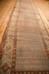 Long perspective view of a vintage Bijar runner's repeating boteh pattern in dusty teal and rust.