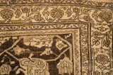 Corner detail of an antique Bijar rug showing its worn pile and floral vine border.