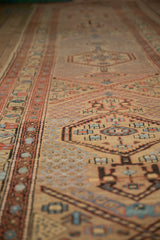 Low perspective along an antique Persian runner showing the textured weave of a geometric medallion and border.