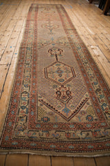 Angled perspective of an antique Persian runner's triple medallion and seeded lattice design.